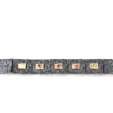 Bracelet articulé argent patiné, composé de 13 éléments rectangulaires, ornés de 5 rectangles or jaune et 3 rubis sertis.
