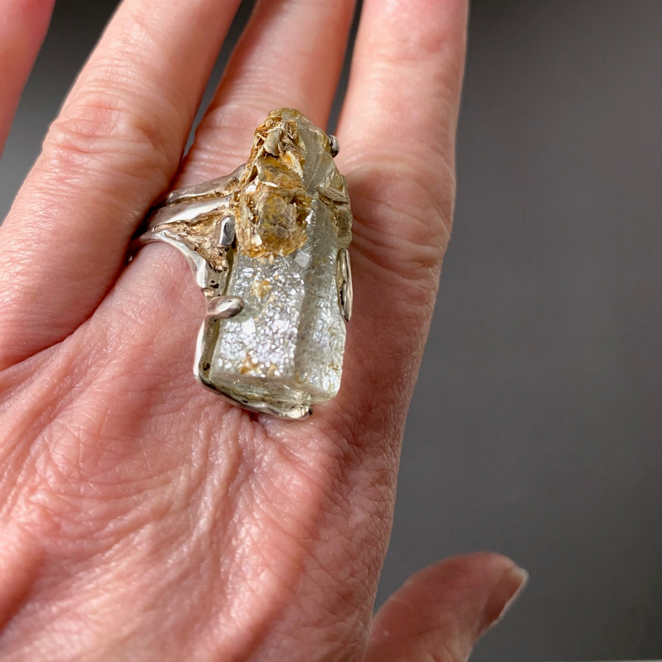 Bague sculpturale en argent ornée d’une Aigue-marine hexagonale avec inclusion de Pyrite. Bague portée sur majeur.