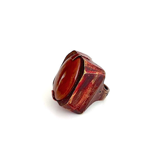 Bague sculpturale en bronze et peinture acrylique rouge, sur le dessus un jaspe rouge ovale est serti par 2 griffes de chaque côté.