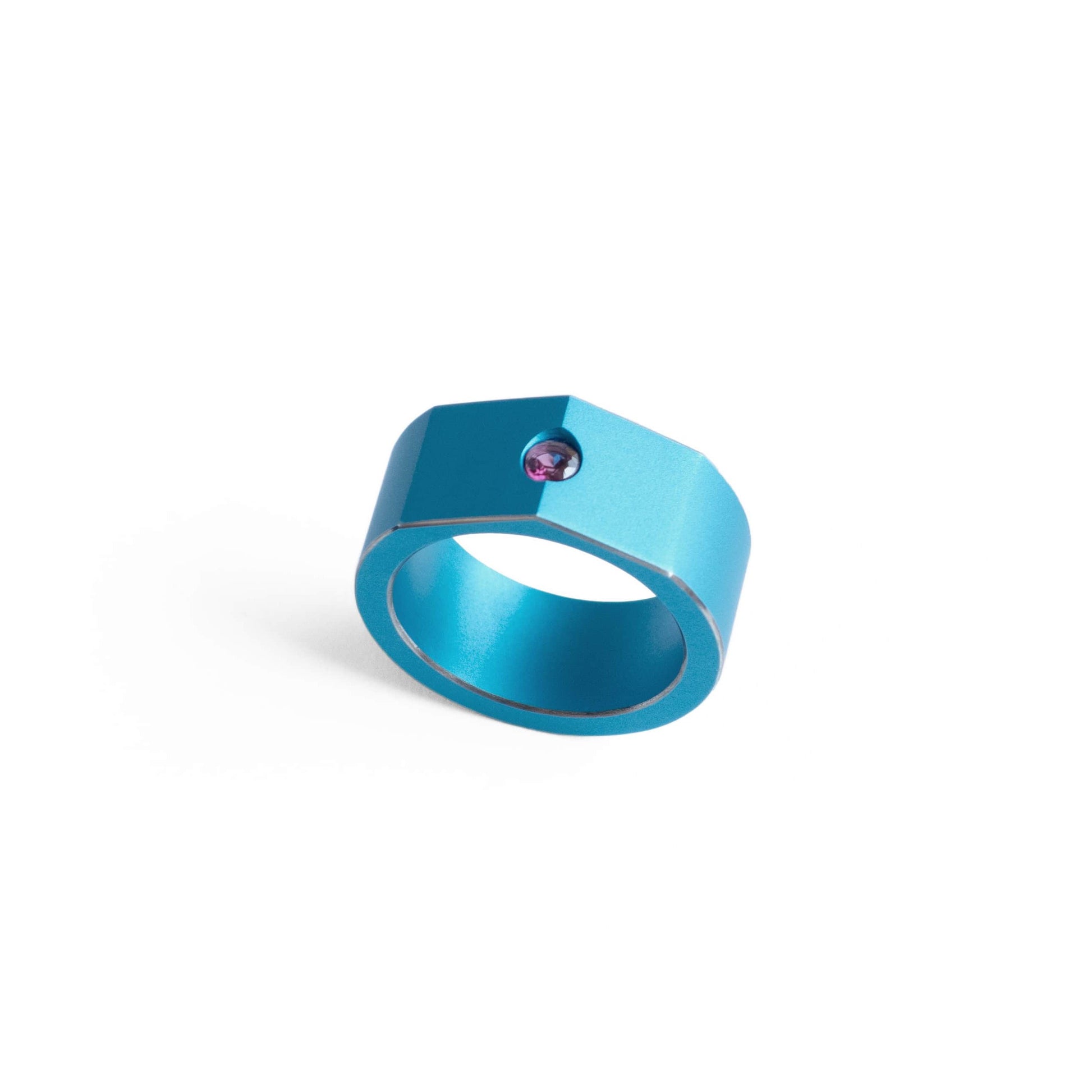 Bague forme de chevalière en aluminium bleu. Sur le sommet biseauté un grenat rhodolite est serti.