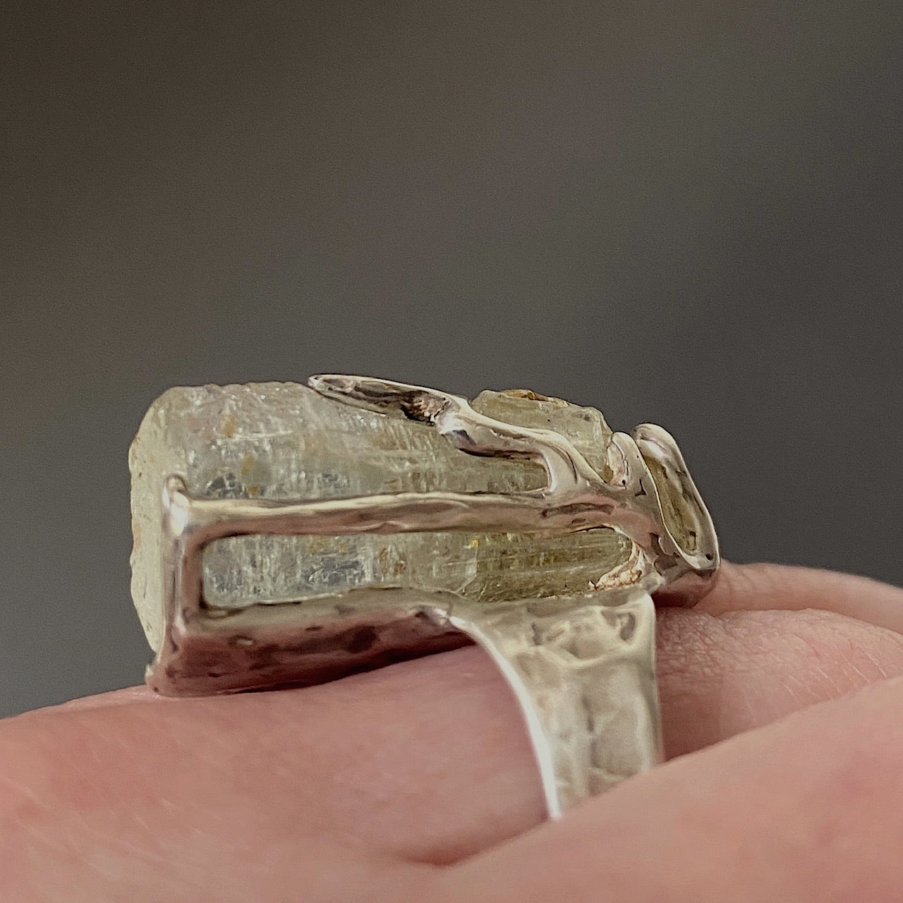 Bague sculpturale en argent ornée d’une Aigue-marine hexagonale. Bague portée, vue de profil.