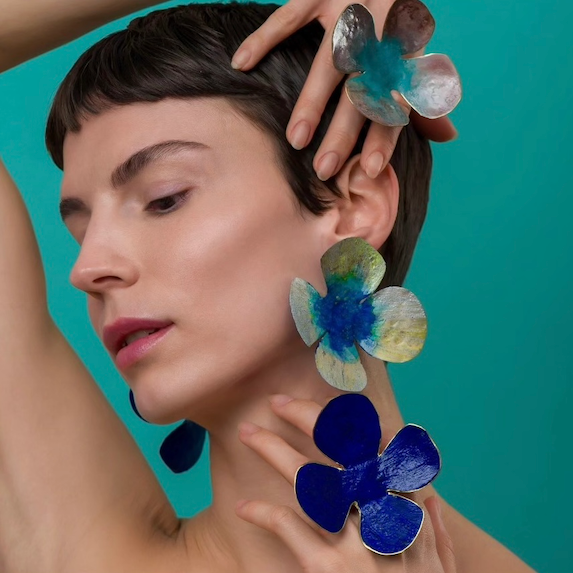 Bagues et boucles d'oreilles grandes fleurs peintes à la main dans les tons de bleus. Bijoux portés.