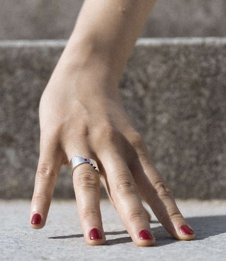 Anneau large en argent rhodié, marqué d'une découpe en escalier. Modèle réversible présentant  d'un côté un saphir rose de l'autre un saphir bleu sur une main de femme.