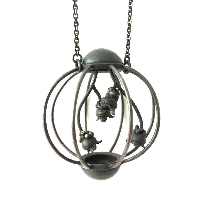 Pendentif cage inspiré par la nature en argent forgé patiné noir, 4 épis semblent pousser à l'intérieur.la chaîne mesure 70 cm