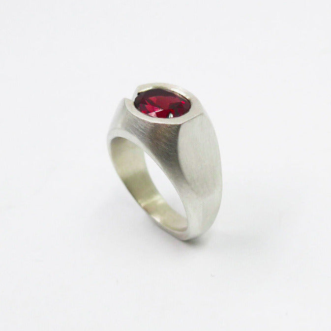 Bague asymétrique en argent, pièce sculptée aux lignes épurées, sertie d'un grenat ovale facetté.