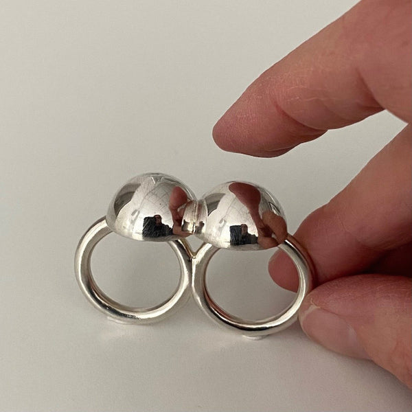 Bague 2 doigts en argent poli. deux demi-sphères liées l'une à l'autre et assemblées par 2 anneaux de même taille. 