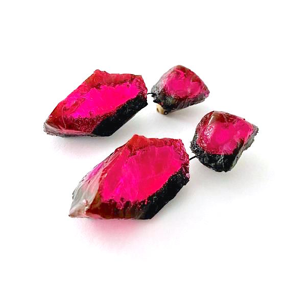 Boucles d'oreilles clips constituées de 2 éléments en résine fushia irisées, reliées par un cable noir.