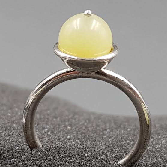 Bague solitaire en argent ornée d'une perle de serpentine jaune, serti clos.